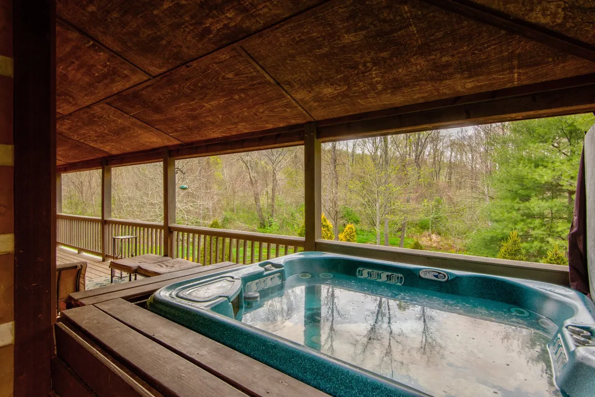 This image captures a serene wooden deck with a bubbling hot tub and sweeping views of the surrounding natural landscape. The deck's sturdy railings and proximity to nature create an inviting space for relaxation, soaking under the stars, or morning coffee with a view.